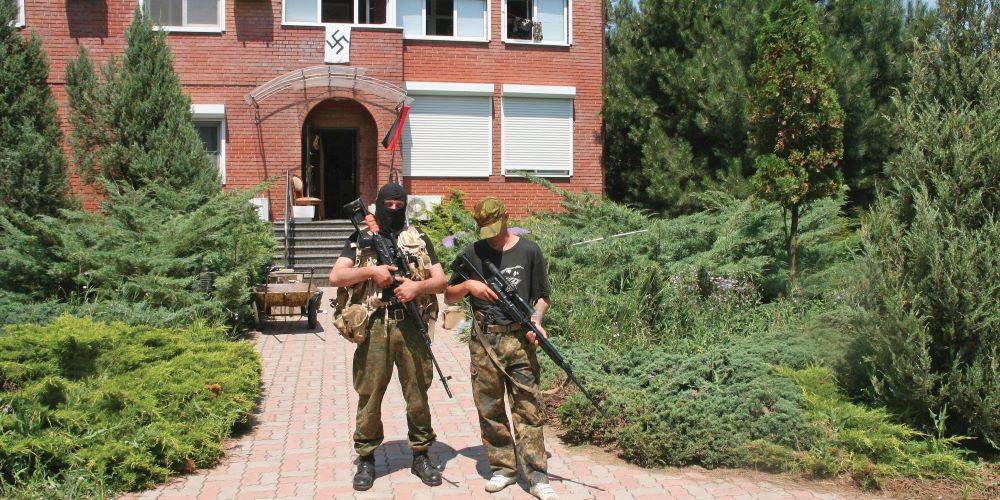 חיילים מגדוד אזוב מול הכניסה לבסיס במריופול, המעוטרת בצלב קרס